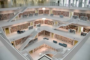 Interior of a modern, multi-level library with open staircases and walls lined with books, symbolizing the depth, structure, and accumulation of process knowledge.