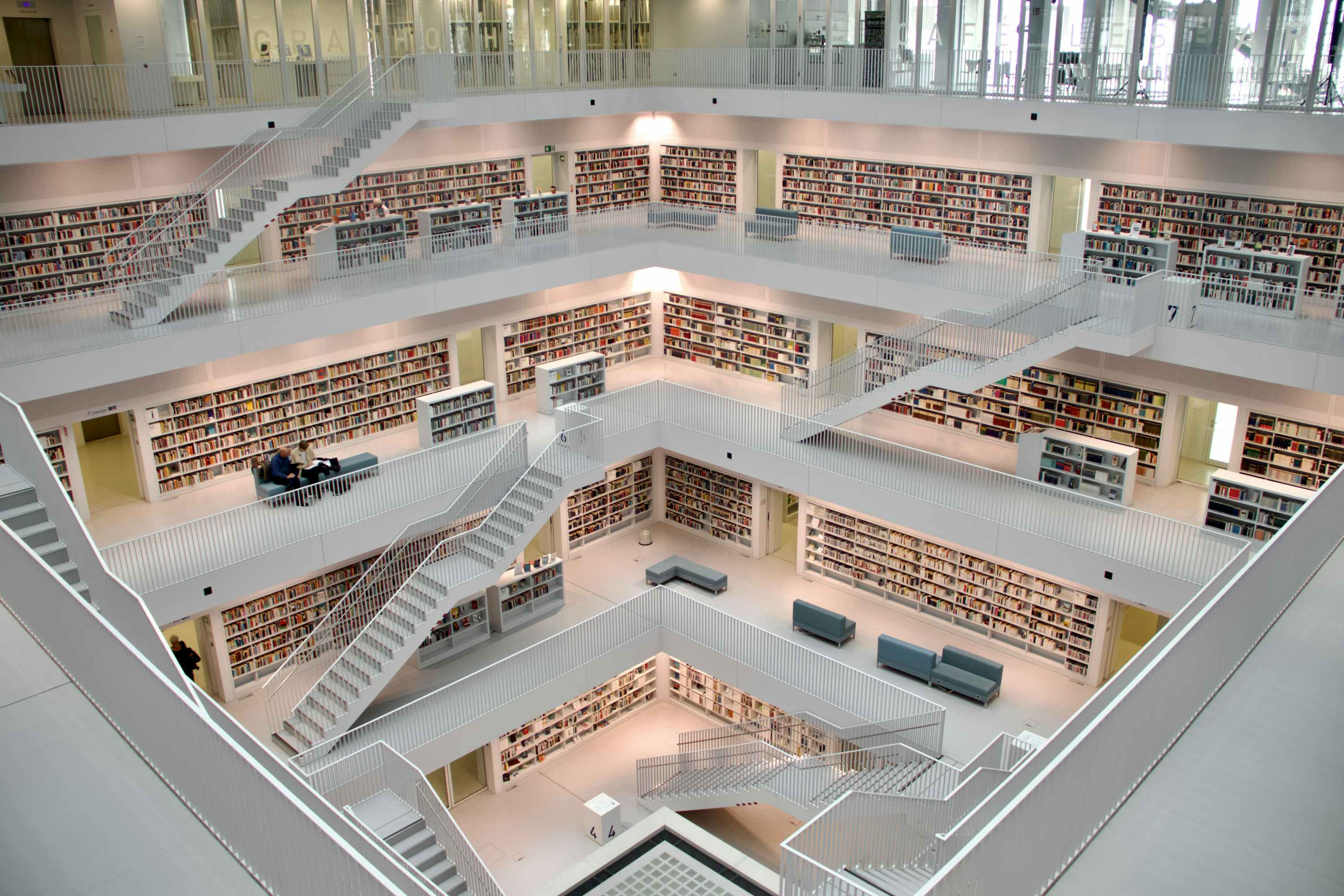 Interior of a modern, multi-level library with open staircases and walls lined with books, symbolizing the depth, structure, and accumulation of process knowledge.